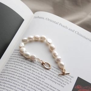 Detailed macro of Baroque pearl bracelet with golden toggle clasp on an open book