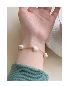 Detail of a gold S925 silver bracelet featuring three white baroque pearls on a wrist