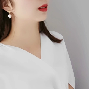 Elegant S925 silver shell pearl earrings on a model, featuring gold tones and white pearls