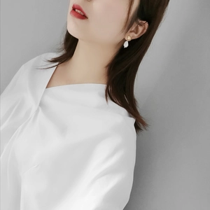 Elegant gold shell stud earrings with white baroque pearl pendants on a female model