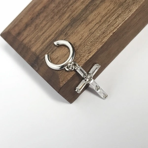 Detail of silver S925 ear cuff with a hanging cross pendant featuring clear zircons