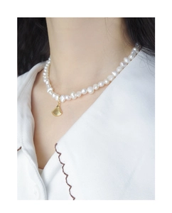 Détail d'un collier de perles d'eau douce avec un pendentif coquille dorée sur un mannequin