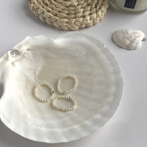 Vue détaillée de trois bagues en perles d'eau douce dans un plateau en coquillage blanc