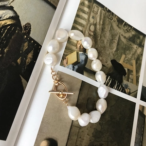 Close-up of Baroque pearl bracelet with golden toggle clasp on a vintage background
