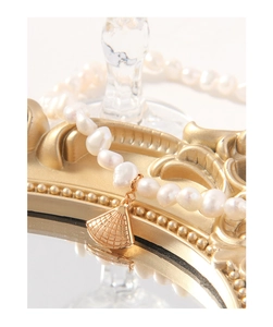 Gros plan d'un collier en perles d'argent S925 avec pendentif en coquillage doré