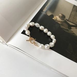 Macro view of Baroque pearl bracelet with golden OT clasp over an art book