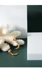 Detailed view of gold crescent moon earrings with irregular molten texture on white stand