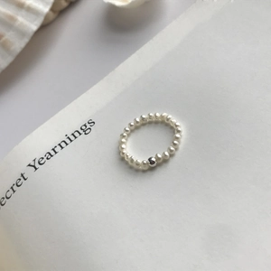 Gros plan d'une bague minimaliste en perles d'eau douce avec une bille en métal argenté
