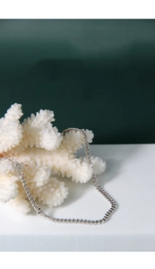 Close-up of minimalist 925 sterling silver curb chain on white coral background
