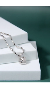 Close-up of heart charm on olive bead chain made of S925 sterling silver with polished finish