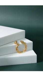 Close-up of golden irregular crescent earrings showing S925 silver stamp and lava texture
