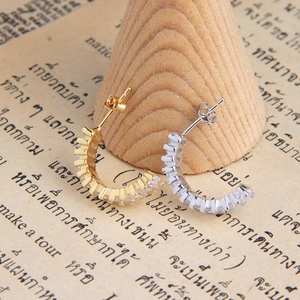 Detailed view of silver and gold C-shaped hoop earrings with square-cut zircon stones