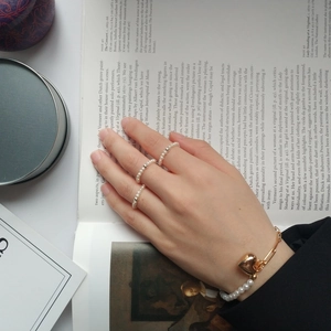 Détail de bagues en perles d'eau douce et bracelet à breloque coeur sur un livre d'art