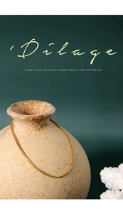 Detailed close-up of a golden snake bone chain bracelet draped over a textured ceramic vase