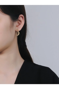 Detailed close-up of crescent moon earrings with vintage embossed gold texture on model