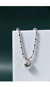 Detail of 925 sterling silver heart charm bracelet with polished oval bead chain link