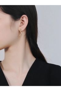 Close-up of a model wearing a golden crescent moon earring with textured finish