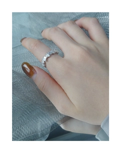 Macro detail of S925 silver ring with baguette-cut zircon stones on a woven background