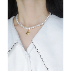 Collier de perles baroques pour femmes avec un pendentif coquillage doré sur chemisier