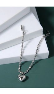 Macro shot of silver sterling heart charm bracelet on white blocks with olive bead chain