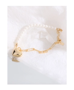 Macro detail of S925 silver tag on a pearl and gold heart charm bracelet