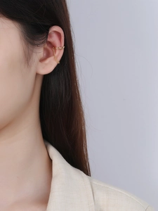 Close-up of S925 sterling silver gold ear cuff with elegant chain on female ear