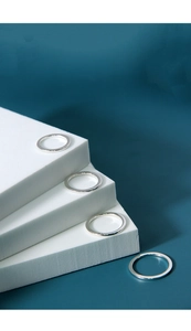 Minimalist S925 sterling silver rings displayed on white geometric blocks over dark background