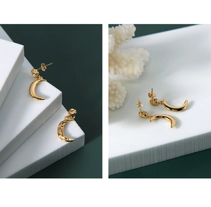 Detailed macro view of gold crescent moon S925 sterling silver earrings with polished finish