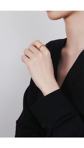 Détail d'une bague dorée torsadée au doigt avec un design minimaliste élégant