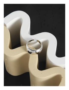 Vue macro d'une bague arc en argent poli minimaliste sur supports ondulés