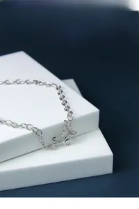 Détail d'une chaîne en argent S925 avec un pendentif papillon évidé au design délicat