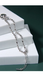 Macro detail of 925 silver heart bracelet with oval beads on green background