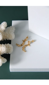 Macro detail of crescent moon gold earrings featuring irregular vintage embossed textures