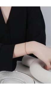 Close-up of minimalist gold snake bone chain bracelet worn on a female wrist