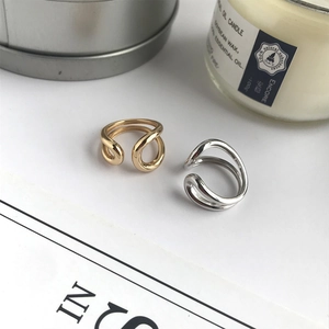 Detail of minimalist gold and silver double-line open rings on a clean aesthetic background