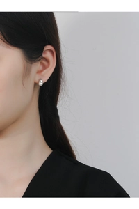 Close-up of minimalist pearl stud earring with a tulip-inspired silver streamline base
