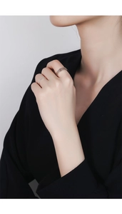 Close-up of minimalist 925 sterling silver layered rings worn by a model in black outfit