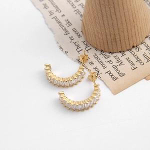 Macro detail of gold C-shaped hoop earrings featuring rectangular cubic zirconia inlay