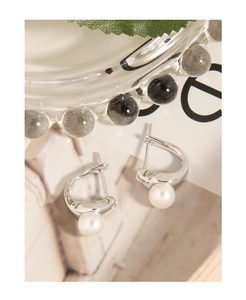 Detailed close-up of S925 silver streamlined earrings with round white pearls and mirror polish
