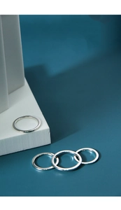 Detailed close-up of four minimalist 925 sterling silver rings on a geometric stone base