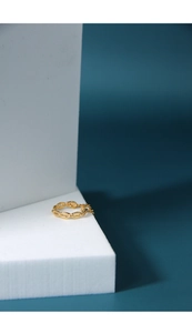 Close-up of golden Cuban link chain ring displayed on a minimalist white pedestal