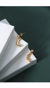 Detail of gold crescent moon earrings featuring smooth and hammered texture finishes