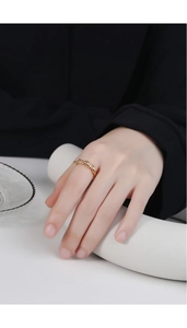 Gros plan d'une bague en corde dorée minimaliste portée au doigt avec un éclairage élégant