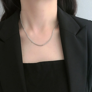 Close-up of minimalist silver curb chain choker necklace on model with black suit