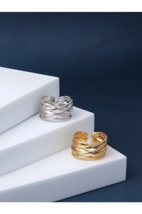 Detail view of multi-layer winding silver and gold rings on white geometric steps