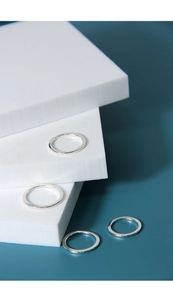 Macro detail showing four polished S925 sterling silver minimalist rings on geometric blocks