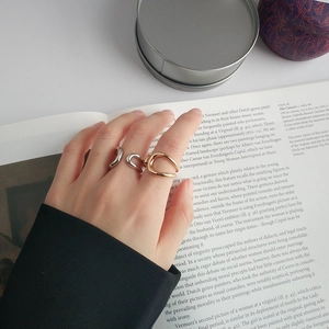 Detailed view of minimalist gold and silver hollowed geometric rings on hands