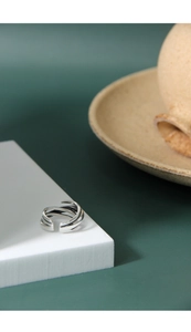 Detail of S925 sterling silver multilayer winding ring on a white geometric stand