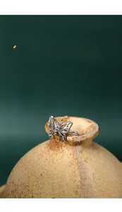 Macro view of silver butterfly ring with hollow-out wings on a ceramic vase