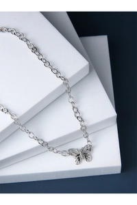 Détail d'un collier pendentif papillon en argent sur des blocs blancs et fond bleu profond
